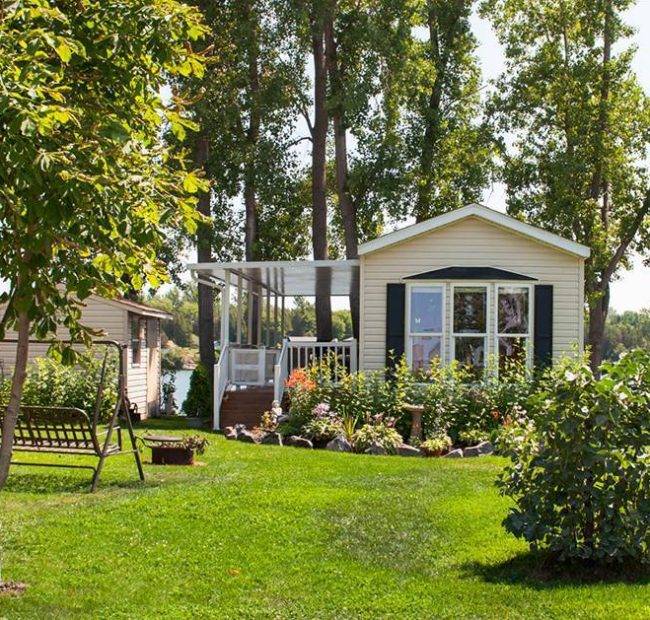 A lakeside cottage with a covered deck and landscaped garden at a Great Blue Resorts property in Ontario