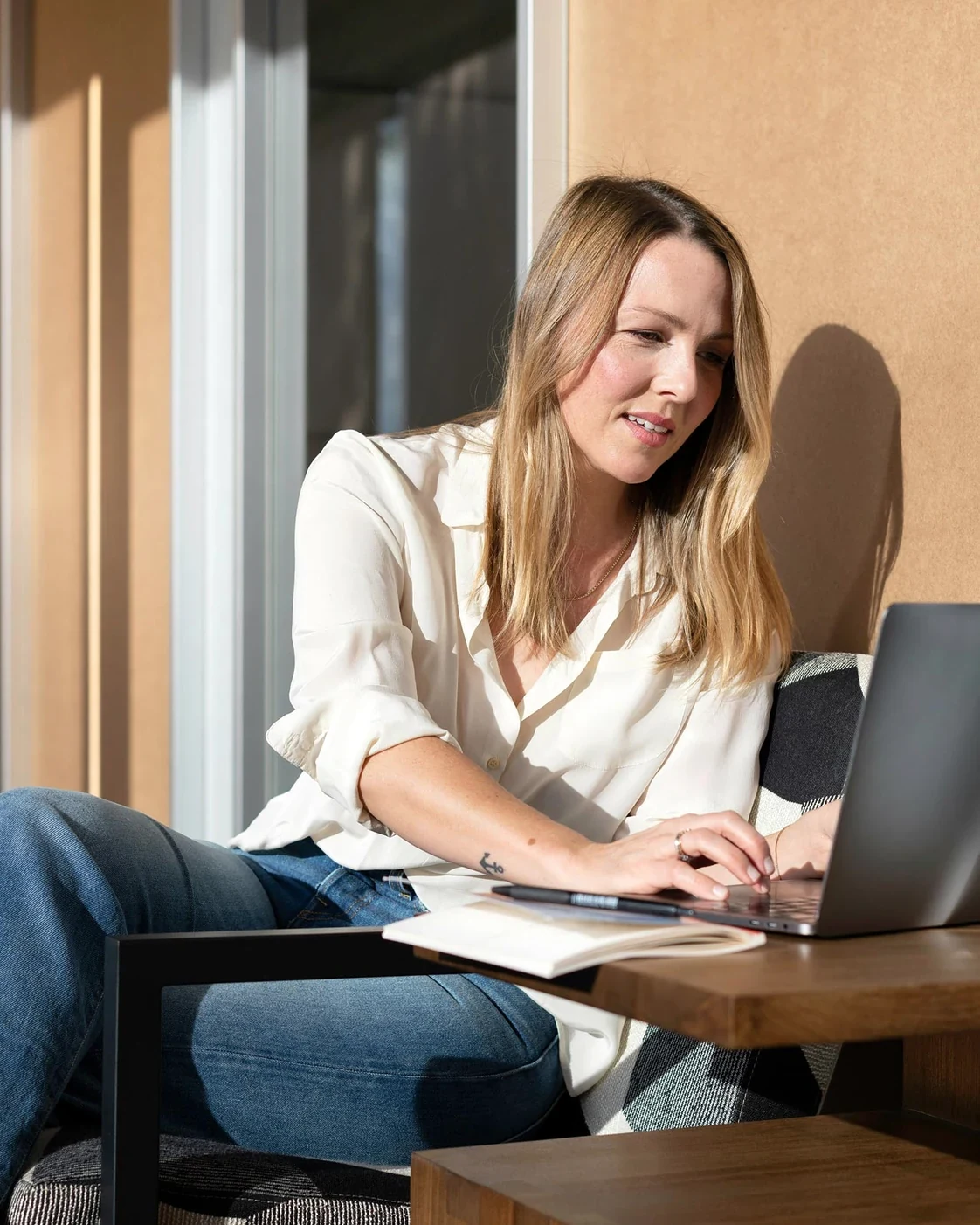 Woman working on a laptop in a sunlit workspace